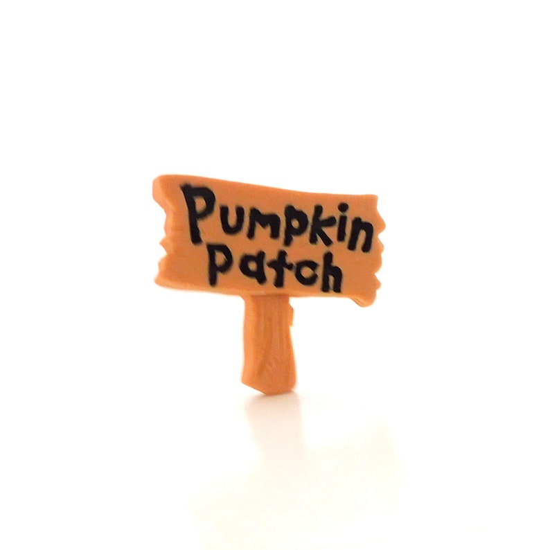 K&ouml;nnte beinhalten: Ein kleines Holzschild mit braunem Hintergrund und schwarzem Text, auf dem "Pumpkin Patch" steht.