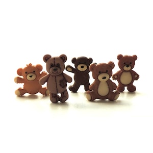 May include: Five small teddy bear buttons in various shades of brown. The buttons are made of plastic and have a flat back.