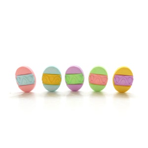 Puede incluir: Cinco botones redondos de color pastel con un diseño decorativo. Los botones son rosa, azul claro, lavanda, verde y amarillo.