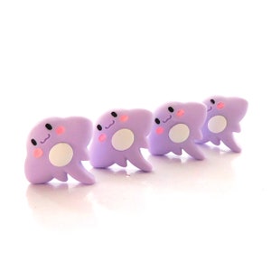 May include: Four purple clay figurines shaped like cartoon clouds with white eyes, pink cheeks, and white centers.