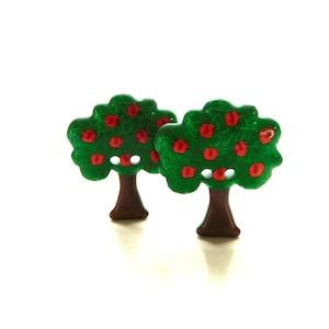 May include: Two green apple tree buttons with red apples. The buttons have brown stems and are made of plastic.