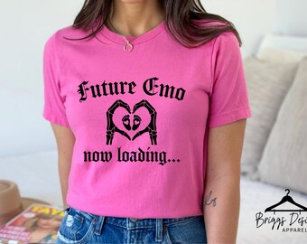 May include: A bright pink t-shirt with the words "Future Emo" in gothic font above a black graphic of skeleton hands forming a heart around baby feet. The phrase "now loading..." is below the graphic.