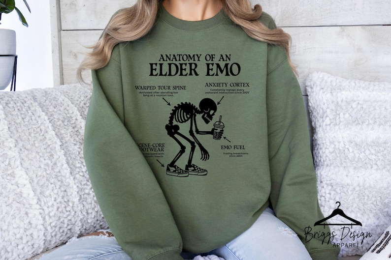 May include: Olive green sweatshirt with the text "ANATOMY OF AN ELDER EMO" and a skeleton graphic. The graphic includes labels for "Warped Tour Spine", "Anxiety Cortex", "Scene-Core Footwear", and "Emo Fuel".