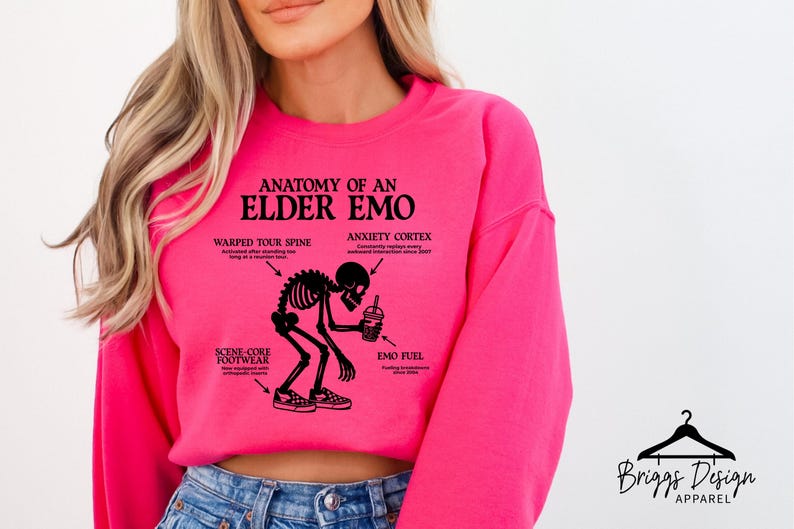 May include: A bright pink sweatshirt with the text "ANATOMY OF AN ELDER EMO" and a black graphic of a skeleton. The graphic includes labeled body parts like "WARPED TOUR SPINE" and "ANXIETY CORTEX". The sweatshirt also features the "Briggs Design Apparel" logo.