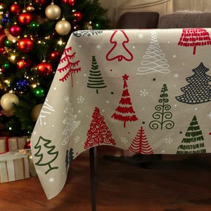 Puede incluir: Un mantel beige con un patrón de árbol de Navidad. El mantel presenta árboles de Navidad estilizados en rojo, verde y blanco sobre un fondo beige.