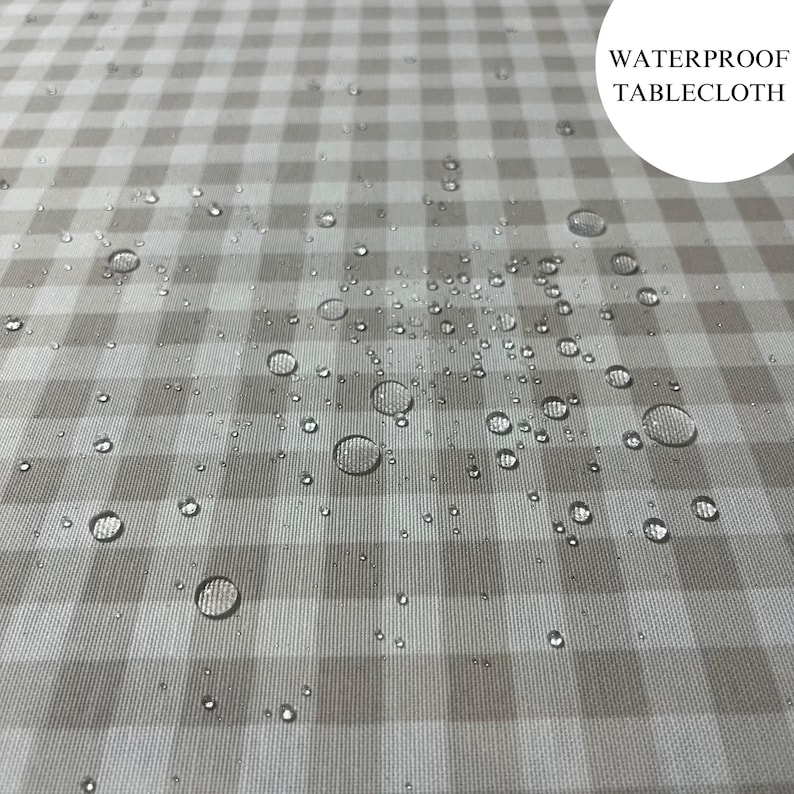 May include: A close-up of a white and gray gingham tablecloth with water droplets on the surface. The text "WATERPROOF TABLECLOTH" is visible in the upper right corner of the image.