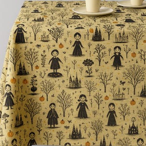 Könnte beinhalten: Beige Tischdecke mit einem sich wiederholenden Muster aus schwarzen Silhouetten von Mädchen, Bäumen, Kürbissen und Burgen. Zwei cremefarbene Tassen und Untertassen stehen auf dem Tisch. Der Stoff hat eine strukturierte Oberfläche.