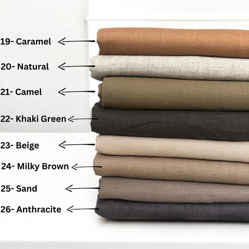 Op de afbeelding: Een stapel van acht stofstalen in verschillende tinten bruin, beige en grijs. De stalen zijn gelabeld met nummers en kleurennamen, waaronder Caramel, Natuurlijk, Camel, Khaki Groen, Beige, Melkbruin, Zand en Anthraciet.