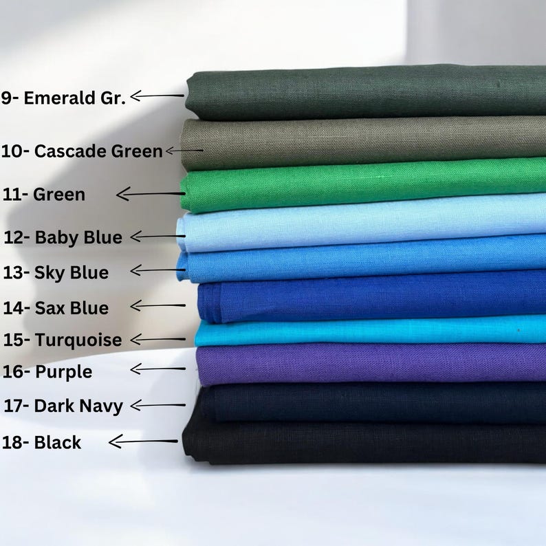 Op de afbeelding: Een stapel stofstalen in verschillende kleuren, waaronder smaragdgroen, cascadegroen, groen, babyblauw, hemelsblauw, saxblu, turquoise, paars, donkerblauw en zwart. De stalen zijn genummerd en met de kleurnaam gelabeld.