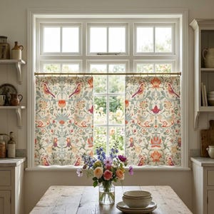 May include: A pair of cafe curtains featuring a repeating pattern of birds and floral motifs in shades of orange, sage green, and cream. The curtains are hung on a thin brass rod across a multi-paned window, displaying a symmetrical design.