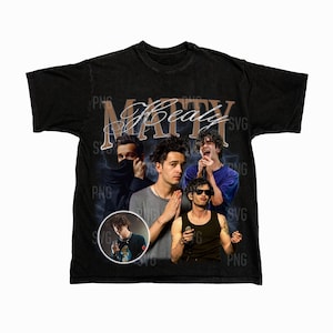 May include: Black t-shirt featuring a collage of images and the name "Matty Healy" in a vintage style. The design includes multiple images of a person, with a circular image at the bottom left.