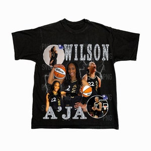 Puede incluir: Camiseta negra con un diseño brillante que presenta el nombre "Wilson A'Ja" e imágenes de jugadoras de baloncesto que llevan camisetas con la palabra "Aces" en ellas.