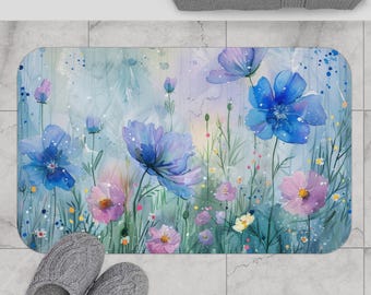 May include: A rectangular bath mat featuring a watercolor floral design. The mat showcases blue, purple, and pink flowers amidst green foliage, with a light blue and green background. Gray slippers are at the bottom.