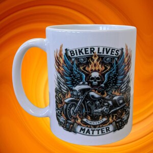 以下が含まれることがあります： バイクのデザイン、スカル、翼、炎が描かれた白いセラミックマグ。テキスト「BIKER LIVES MATTER」と「BORN FREE」が表示されています。マグカップにはカーブしたハンドルが付いています。背景はオレンジ色です。