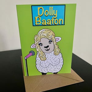 May include: A green card with a cartoon sheep wearing a blonde wig and holding a microphone. The card has the text "Dolly Baaton" in a blue box.