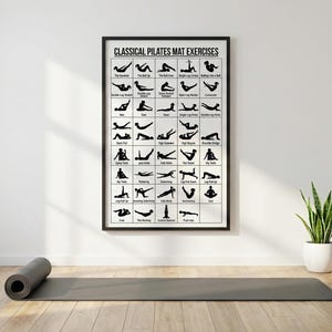 以下が含まれることがあります： 「CLASSICAL PILATES MAT EXERCISES」と書かれた額入りのポスターが白い壁に掛けられており、さまざまなピラティスのエクササイズの黒いシルエットイラストが表示されています。丸められた灰色のエクササイズマットと鉢植えの植物が木製の床に置かれています。
