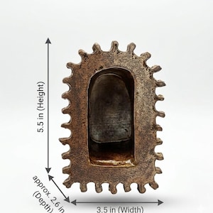 Pu&ograve; includere: Un oggetto marrone testurizzato a forma di arco con un bordo smerlato. L'oggetto misura 13,97 cm di altezza, 8,89 cm di larghezza e circa 6,6 cm di profondit&agrave;, come indicato dalle etichette di misurazione stampate sull'immagine.