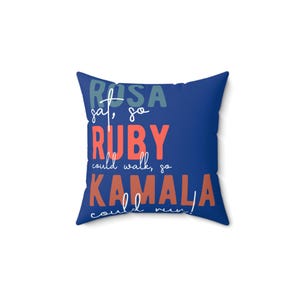 Op de afbeelding: Een blauw kussen met de tekst "Rosa sat, so Ruby could walk, so Kamala could run!" in kleurrijke letters.