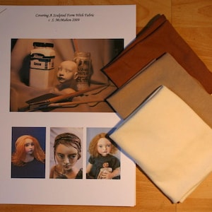 May include: A printed page with the title "Covering A Sculpted Form With Fabric" and three fabric swatches in shades of brown and beige. The page features a photo of art supplies and three doll portraits.