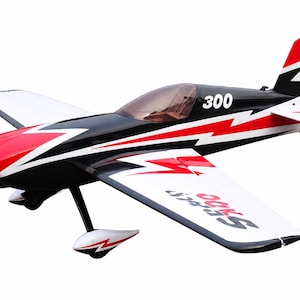 Puede incluir: Un modelo de avión acrobático radiocontrolado con un patrón gráfico de rayos en negro, rojo y blanco. El fuselaje está marcado con el número 300 y las alas muestran el texto Sbach. Incluye una hélice marrón y un tren de aterrizaje.