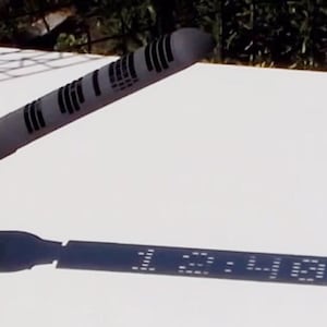 Può includere: Una meridiana nera e grigia con un'ombra che indica le "12:41".