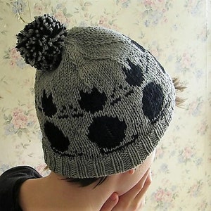 May include: Gray knitted beanie with a black pom pom and a black and white geometric pattern.