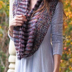May include: A woman wearing a light blue long-sleeved shirt with a crocheted lace trim on the sleeves. She is wearing a colorful striped and textured scarf around her neck.