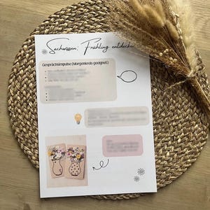 May include: A white paper with the text "Sachwissen: Fr&uuml;hling entdecken" and "Gespr&auml;chsimpulse (Morgenkreis geeignet)". The paper has illustrations of vases with flowers and a lightbulb. A bundle of dried flowers rests on the right.