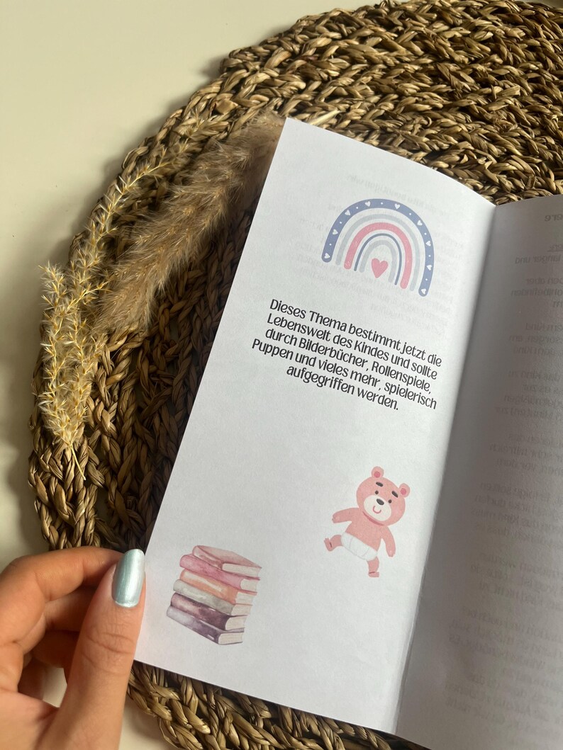 May include: A page from a book with a rainbow illustration and the text "This theme determines the child's world now and should be addressed through picture books, role-playing, dolls, and much more in a playful way."