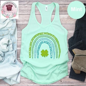 May include: A white ceramic mug with a black handle and the text "But First, Coffee" in a bold, black font. The mug is set against a blurred background, highlighting its simple design.