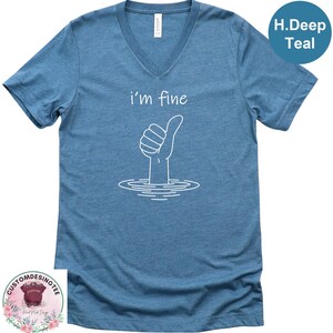 A blue t-shirt with a white graphic design depicting a hand giving a thumbs up, with the text "i'm fine" below the graphic.