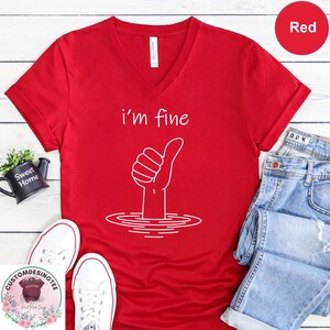a red t-shirt with a white graphic design, a pair of jeans, a pair of white sneakers, and a small plant.