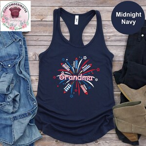 May include: Midnight navy tank top with a graphic of fireworks and the word "Grandma" in red and white. Names of family members are included in the firework design. A casual, patriotic design.