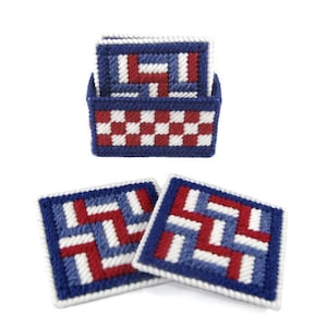 Puede incluir: Conjunto de cuatro posavasos tejidos en rojo, blanco y azul con un patrón geométrico. Los posavasos están en un soporte con un patrón a cuadros.