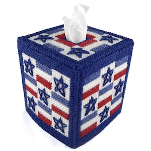 May include: A blue and white tissue box cover with red stripes and stars. The cover is made of fabric and has a crocheted design.