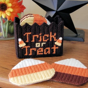 May include: A brown and orange crocheted candy corn container with the words "Trick or Treat" on the front. The container is filled with crocheted candy corn pieces.