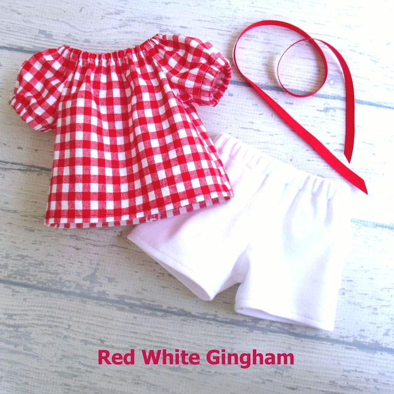 This summer set for your 18 inch doll includes a red and white gingham shirt with white stretch knit shorts, and a length of red grosgrain ribbon your doll can use as a hair tie.