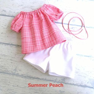 This set for your 18 inch doll includes a cotton top in a peach color with uneven white plaid lines.  It comes with a pair of white stretch knit shorts and a length of peach suede cord your doll can use as a hair tie.