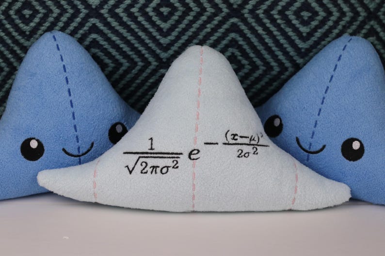 May include: Three blue plush triangle pillows with embroidered faces. The middle pillow has a mathematical formula embroidered on it: "1/&radic;2&pi;&sigma;&sup2; e^-(x-&mu;)&sup2;/2&sigma;&sup2;".