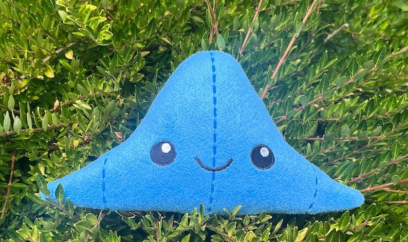 May include: A blue plush toy shaped like a blob with a smiling face and embroidered eyes.