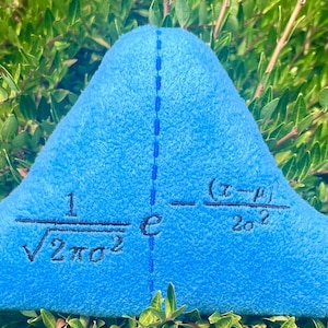 May include: A blue plush pillow shaped like a bell curve with the mathematical formula for a normal distribution embroidered on it. The formula is 1/&radic;2&pi;&sigma;&sup2; * e^-(x-&mu;)&sup2;/2&sigma;&sup2;.