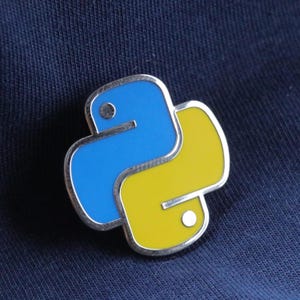 以下が含まれることがあります： 青と黄色の Python ロゴがついた銀色の金属製のピン。ロゴは、青い体と黄色の頭を持つスタイリッシュなヘビです。