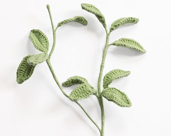 May include: Two stems of crocheted leaves in a light green color. The leaves are detailed with textured stitching, and the stems are slender. The background is plain white, highlighting the handmade botanical design.