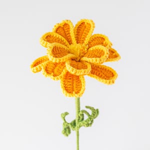 May include: A handcrafted crochet flower with bright yellow petals and a green stem. The flower's petals are intricately detailed, and the stem features small green leaves. The flower is a cheerful, handmade decorative item.
