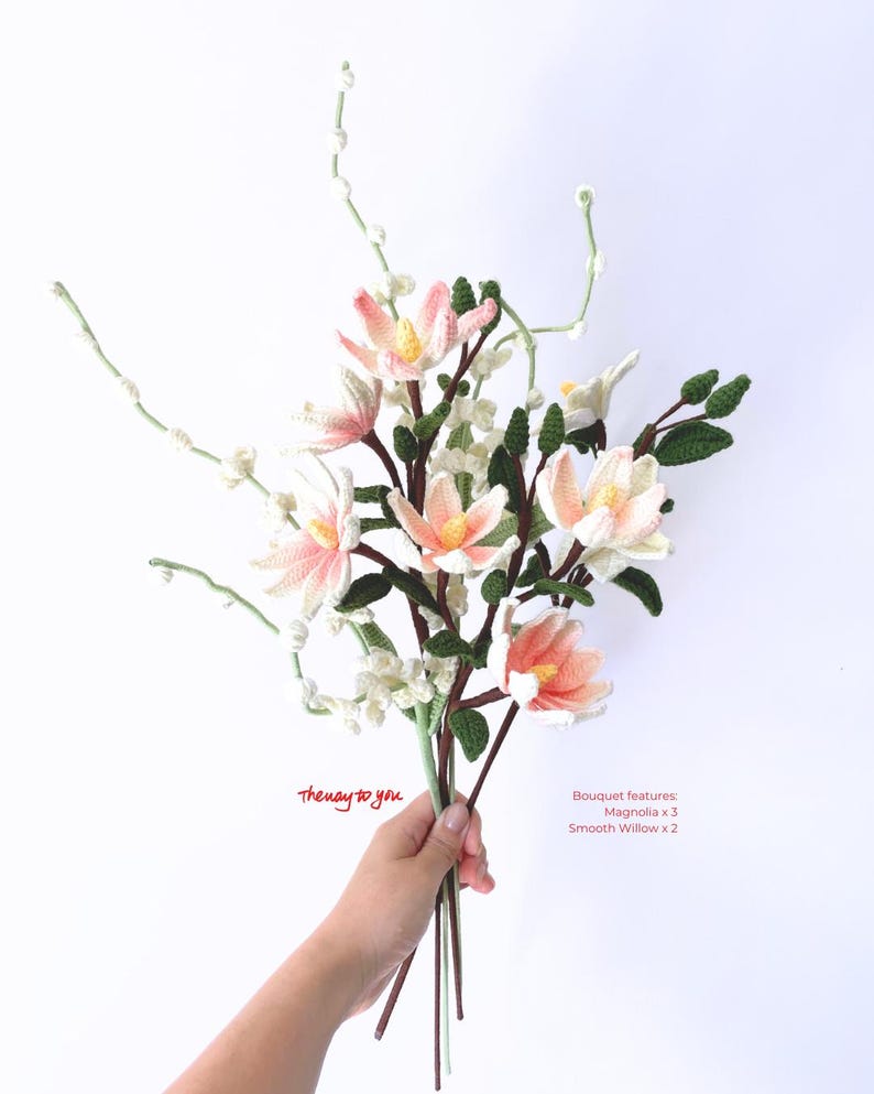 May include: A bouquet of crocheted flowers, including three pink magnolia flowers and two smooth willow branches. The bouquet is held in a hand with the text "the way to you" written below. The bouquet features: Magnolia x 3, Smooth Willow x 2.