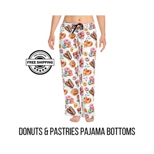 May include: White pajama bottoms with a repeating pattern of donuts, pastries, and sprinkles. The drawstring waist pants feature a variety of baked goods in shades of pink, brown, and teal. The text "DONUTS & PASTRIES PAJAMA BOTTOMS" is printed at the bottom.