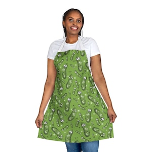 May include: A green apron with a pattern of cartoon pickles. The apron has adjustable straps and a large pocket in the front.