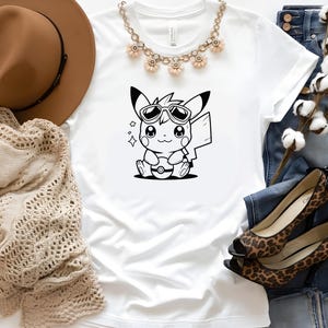 May include: A white t-shirt with a black and white cartoon image of a Pikachu wearing sunglasses and holding a Pokeball. The image is centered on the shirt.