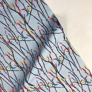 May include: Light blue fabric with a repeating pattern of small pink and yellow flowers and blue birds on branches.