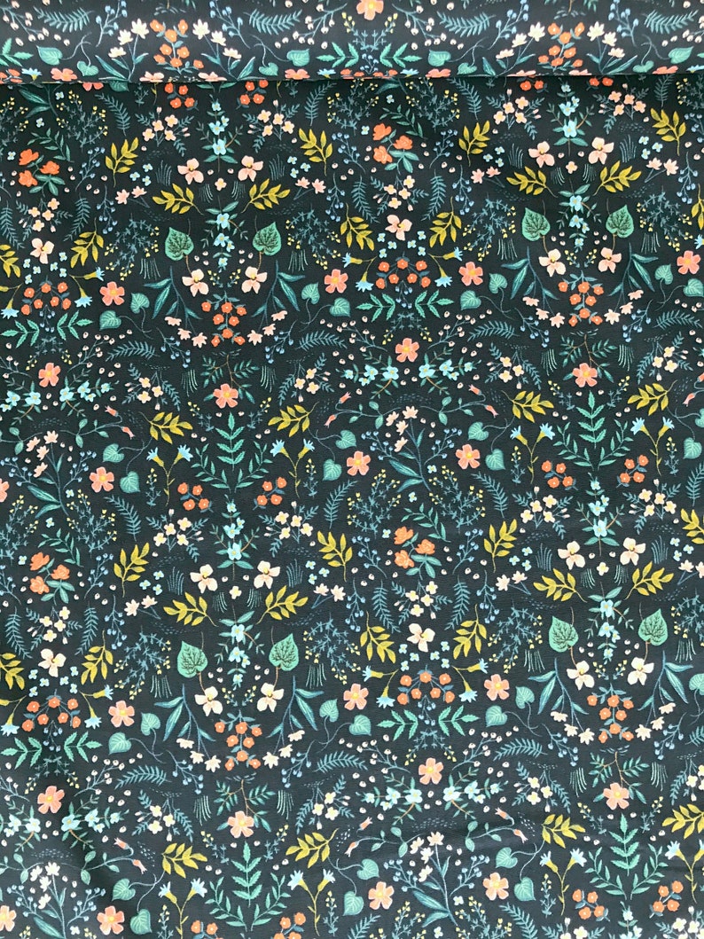 Peut inclure: Tissu bleu canard fonc&eacute; avec un motif floral r&eacute;p&eacute;t&eacute;. Le motif pr&eacute;sente de petites fleurs blanches, p&ecirc;che et bleues, ainsi que des feuilles et des tiges vertes et jaunes. Le tissu est probablement du coton ou une mati&egrave;re similaire, adapt&eacute; aux projets de couture.